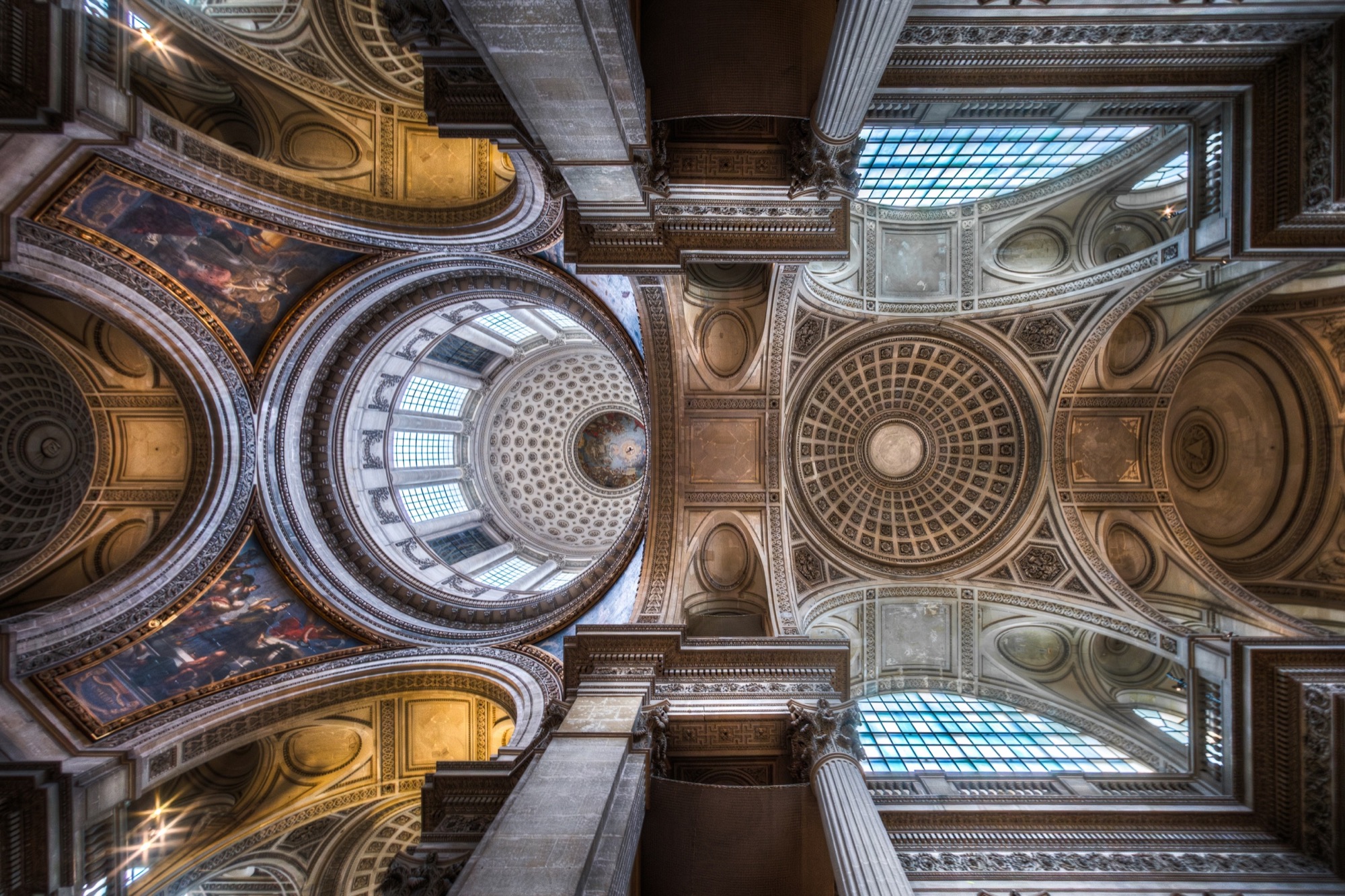 Coupoles et voûtes à caissons d’une église française vues d’en bas, ordonnées symétriquement autour d’une nervure centrale.