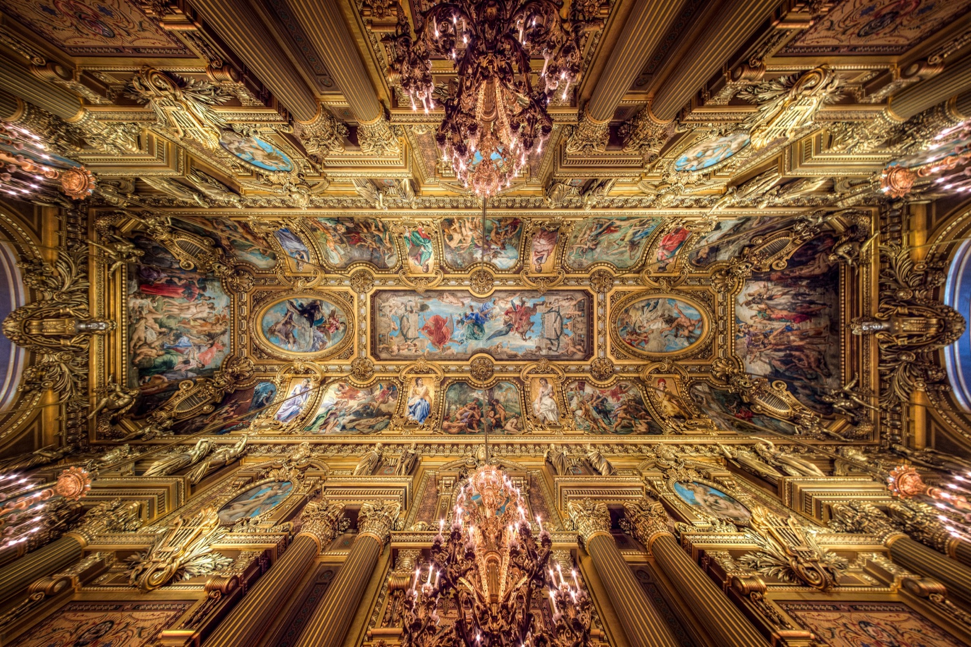 Un plafond doré de panneaux peints et de médaillons ovales, un lustre de cristal suspendu à chaque extrémité, et des colonnes s’élevant de toutes parts.