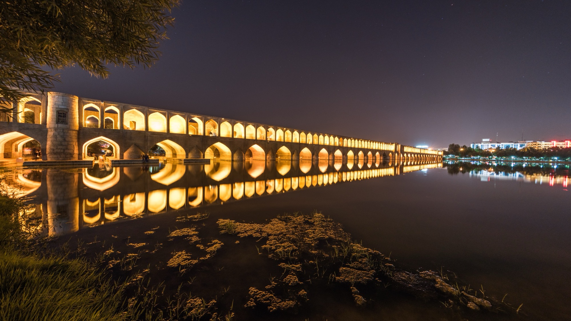 Les arches illuminées du pont Si-o-se Pol sur la rivière Zayandeh, à Ispahan, la nuit.