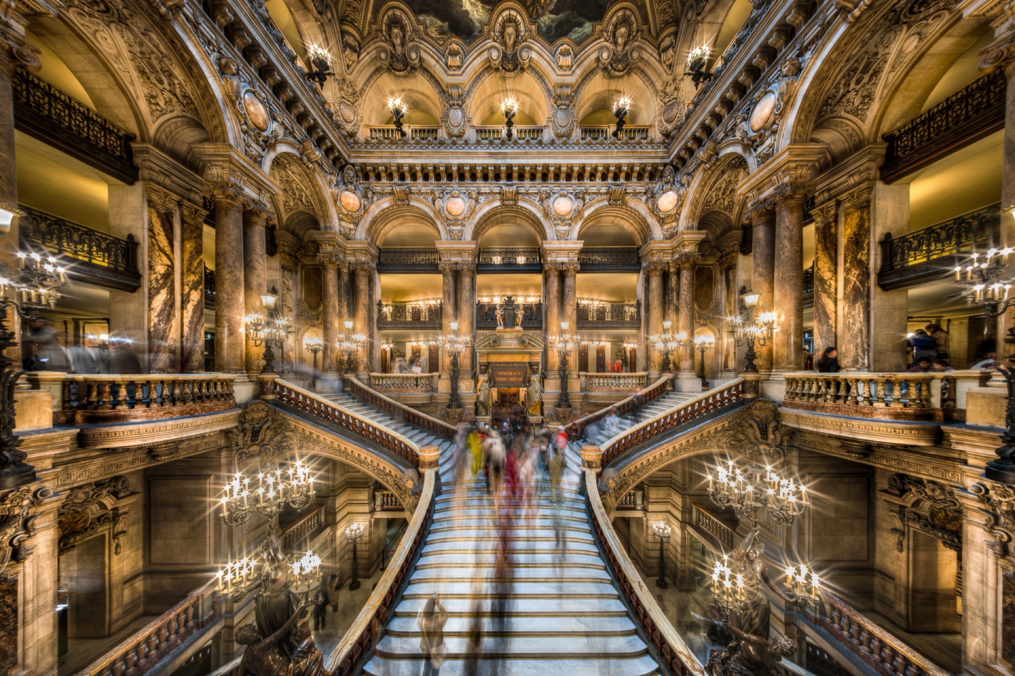 The grand staircase of the Palais Garnier in Paris, visitors dissolved by a long exposure.