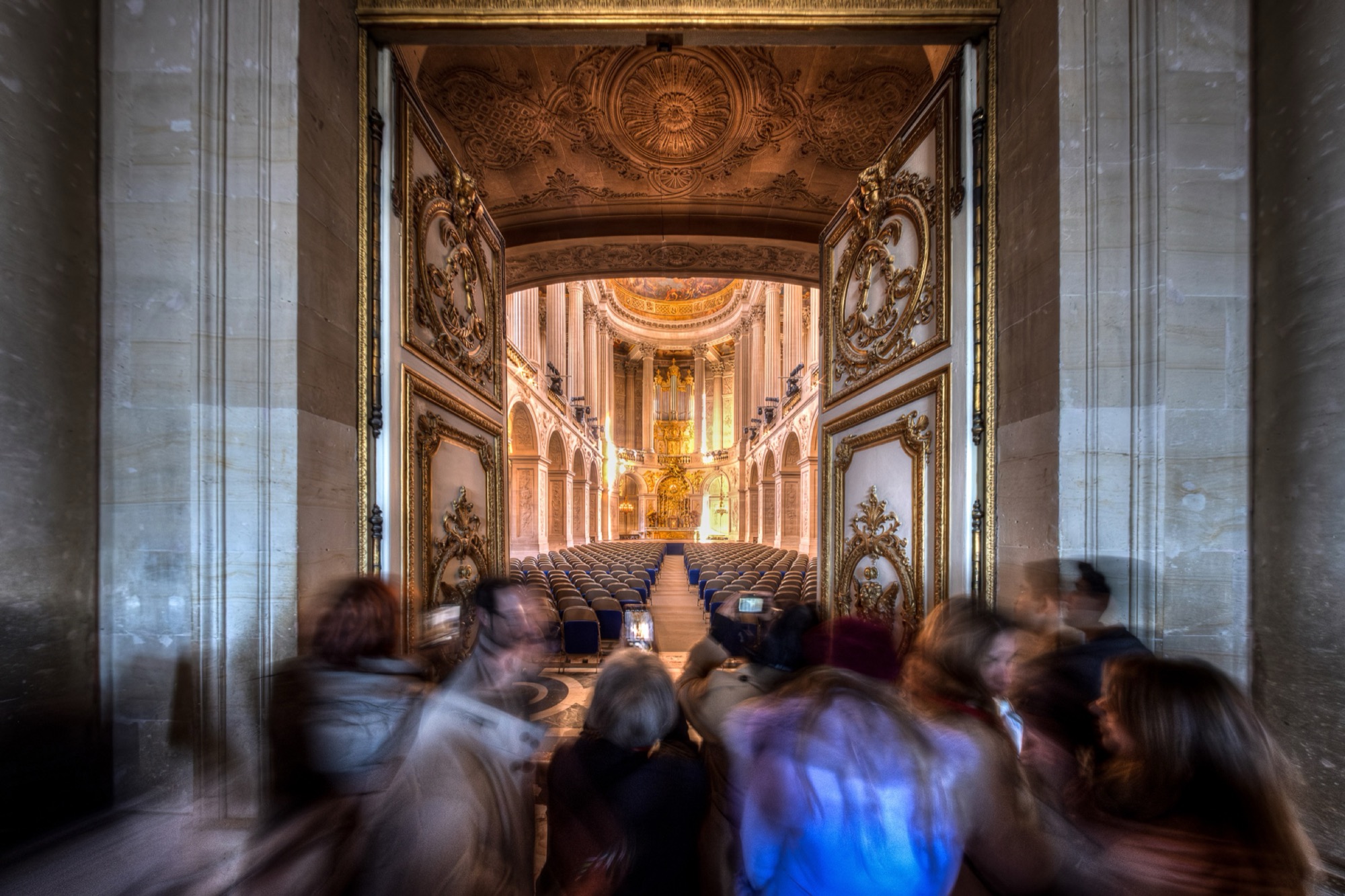 A great French interior photographed in a long exposure: the architecture sharp and still, visitors dissolved into traces of light.