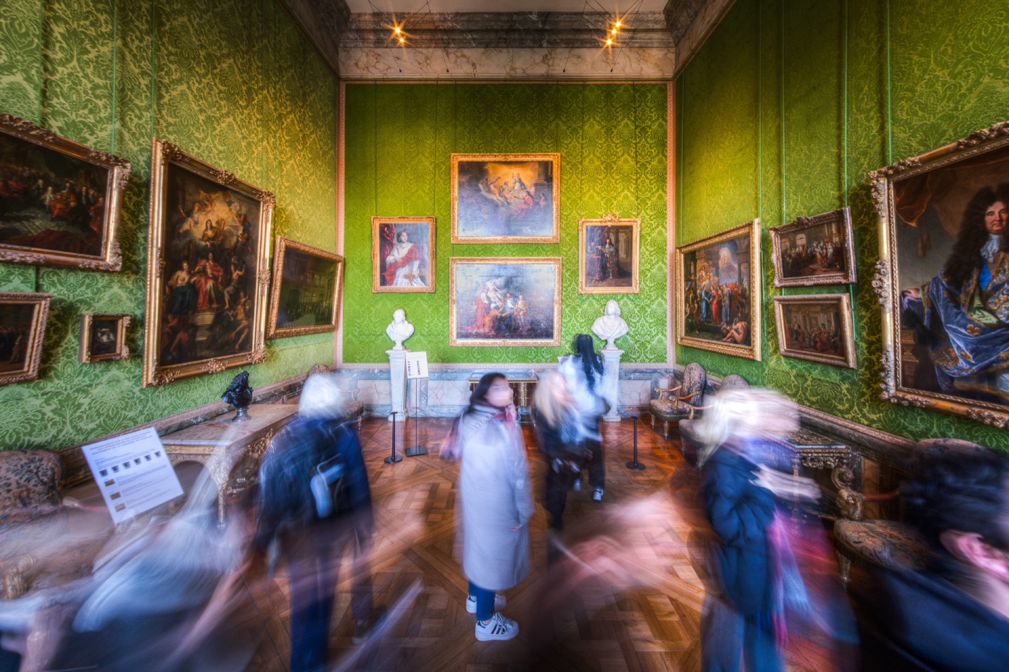 A great French interior photographed in a long exposure: the architecture sharp and still, visitors dissolved into traces of light.