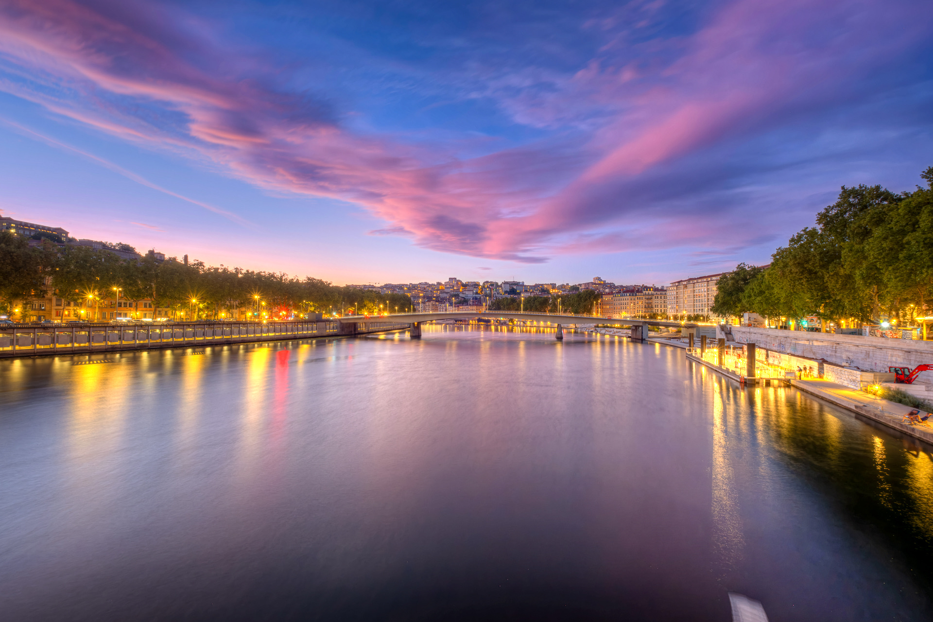 La Saône après le coucher du soleil depuis la passerelle du Palais de Justice, vers l’amont et le pont Maréchal-Juin, sous des nuages roses et violets, les lumières des quais reflétées dans l’eau
