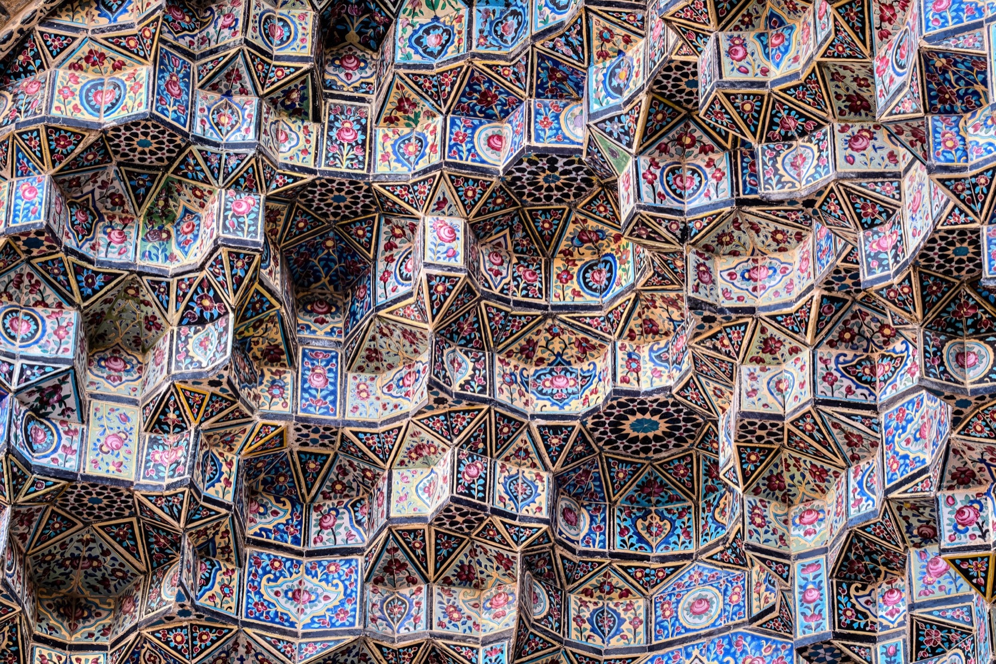 Muqarnas de céramique à motifs floraux rose, bleu et blanc, en une multitude de petits gradins.