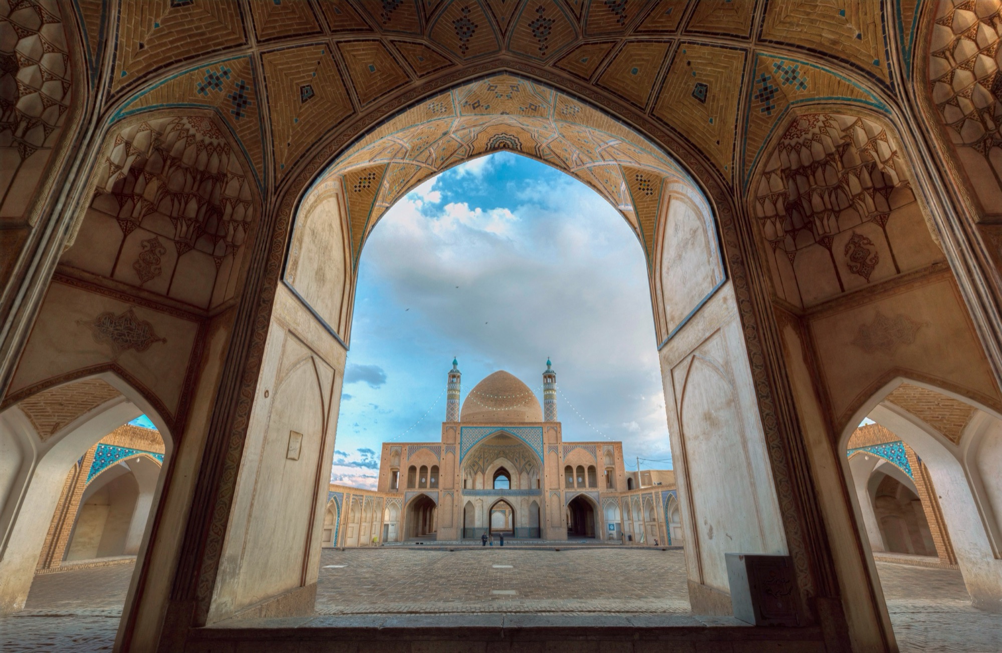 La cour et la coupole de la mosquée Agha Bozorg, à Kachan, encadrées par l’arc d’un iwan latéral.