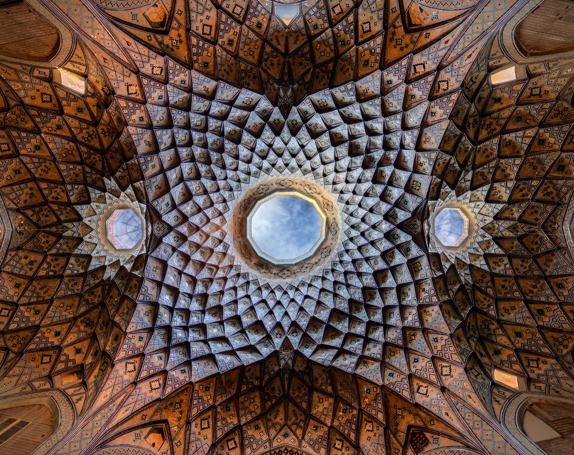 La coupole du timcheh Amin-od-Dowleh, dans le bazar de Kachan : une étoile de brique et de plâtre faite d’alvéoles de muqarnas, autour d’un oculus lumineux ouvert sur le ciel.