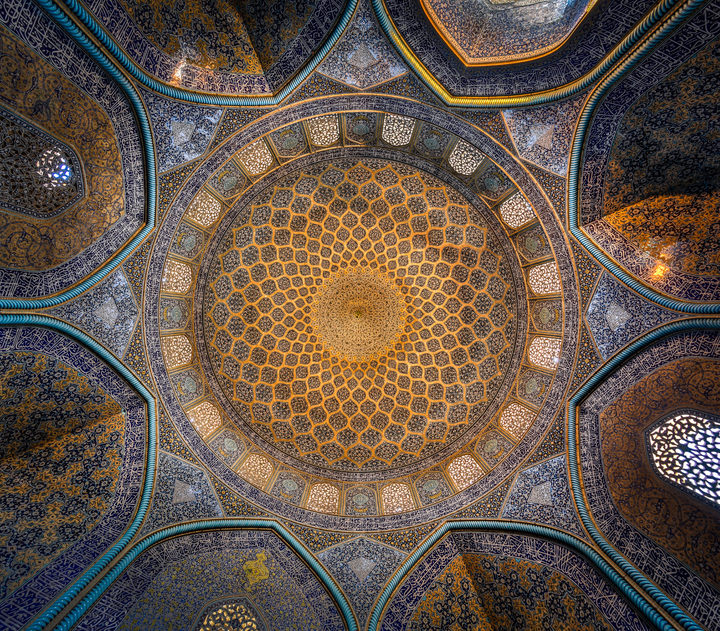 The dome of the Sheikh Lotfollah Mosque, Isfahan, seen from directly below: a golden lattice of tiles narrowing to a central medallion, ringed by turquoise-edged arches.